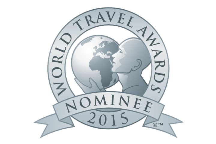 Silver logo featuring a stylized person holding a globe, with text reading "World Travel Awards Nominee 2015" on a circular ribbon design.