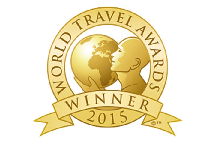 A gold emblem with a person holding a globe, featuring the text "World Travel Awards Winner 2015" on a circular border and ribbon.