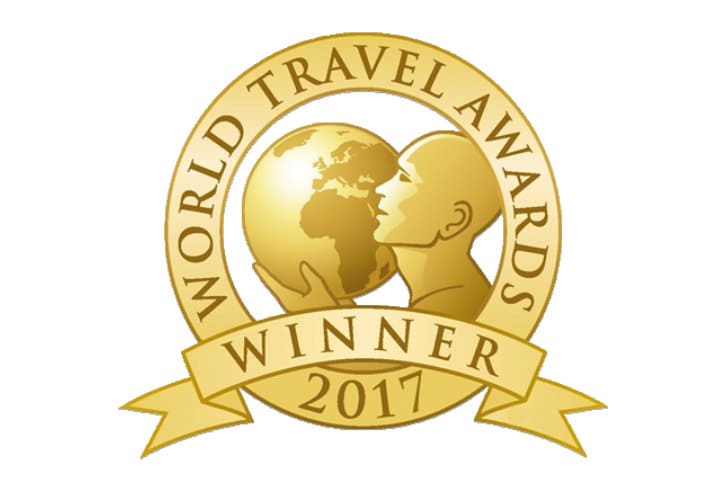 Gold emblem for World Travel Awards Winner 2017, featuring a globe and a stylized human figure within a circular design.