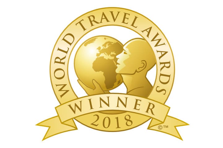 Gold World Travel Awards "Winner 2018" emblem featuring a stylized figure holding a globe, with text wrapped around the circular logo.
