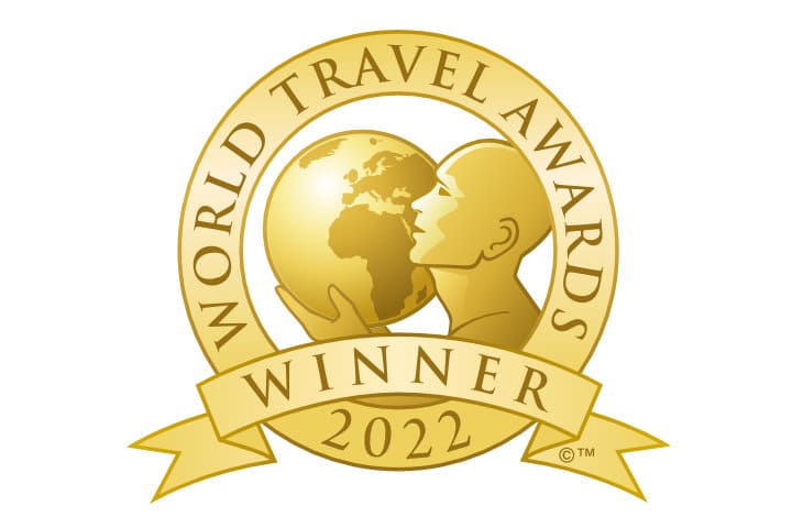 Gold "World Travel Awards Winner 2022" emblem featuring a stylized figure holding a globe, with text in a circular and banner layout.